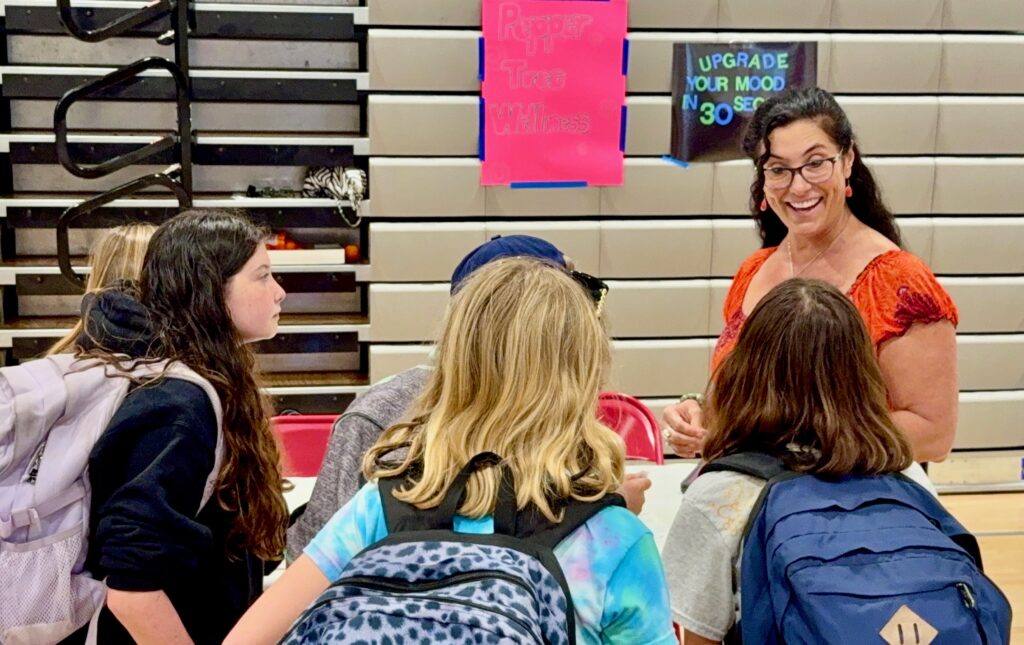 Peppertree Wellness practitioner smiling with teens at a school wellness fair